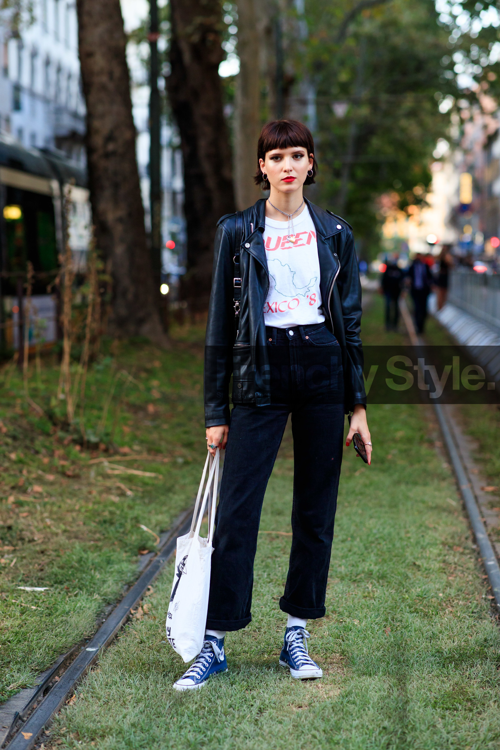 black jeans, black leather perfecto, white t-shirt, letter printed t-shirt, cropped jeans, flare jeans, converse shoes, blue sneakers, high sneakers, silvered earrings, silvered necklace, chain necklace, padlock necklace, hoop earrings, red lipstick, street style, jonathan paciullo, FW, frenchystyle, fashion week, MFW, MILAN, SPRING SUMMER 2021, SS 21, vertical, full length, model