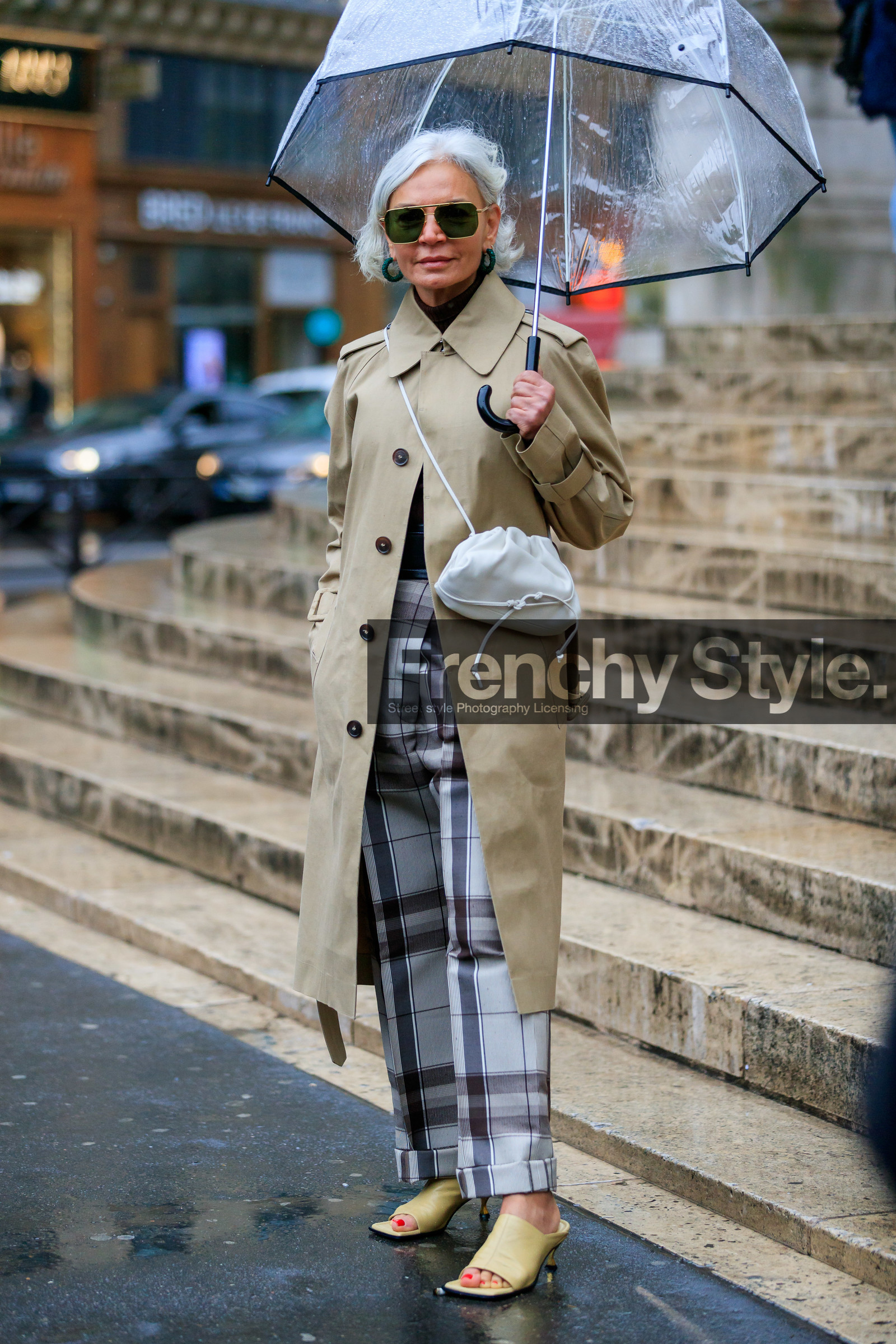 beige trench coat, light beige leather bag, crossbody bag, metalic frame sunglasses, aviator sunglasses, geometric shape glasses, bottega veneta bag, bottega veneta sunglasses, green earrings, hoop earrings, strassed earrings, grey pants, checked pants, brown pants, plaid pants, light yellow leather sandals, kitten heels sandals, kitten heels slippers, sheer umbrella, fashion week, frenchystyle, FW, jonathan paciullo, street style, PFW, PARIS, vertical, full length