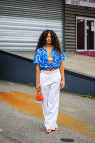 curly hair, blue shirt, printed shirt, coperni shirt, white bra, white trousers, baggy trousers, orange bag, mini bag, orange sandals, coperni, street style, jonathan paciullo, FW, frenchystyle, fashion week, AUTUMN WINTER 2022-2023, FALL WINTER 2022_2023, FW 22-23, PFW, PARIS, full length, vertical