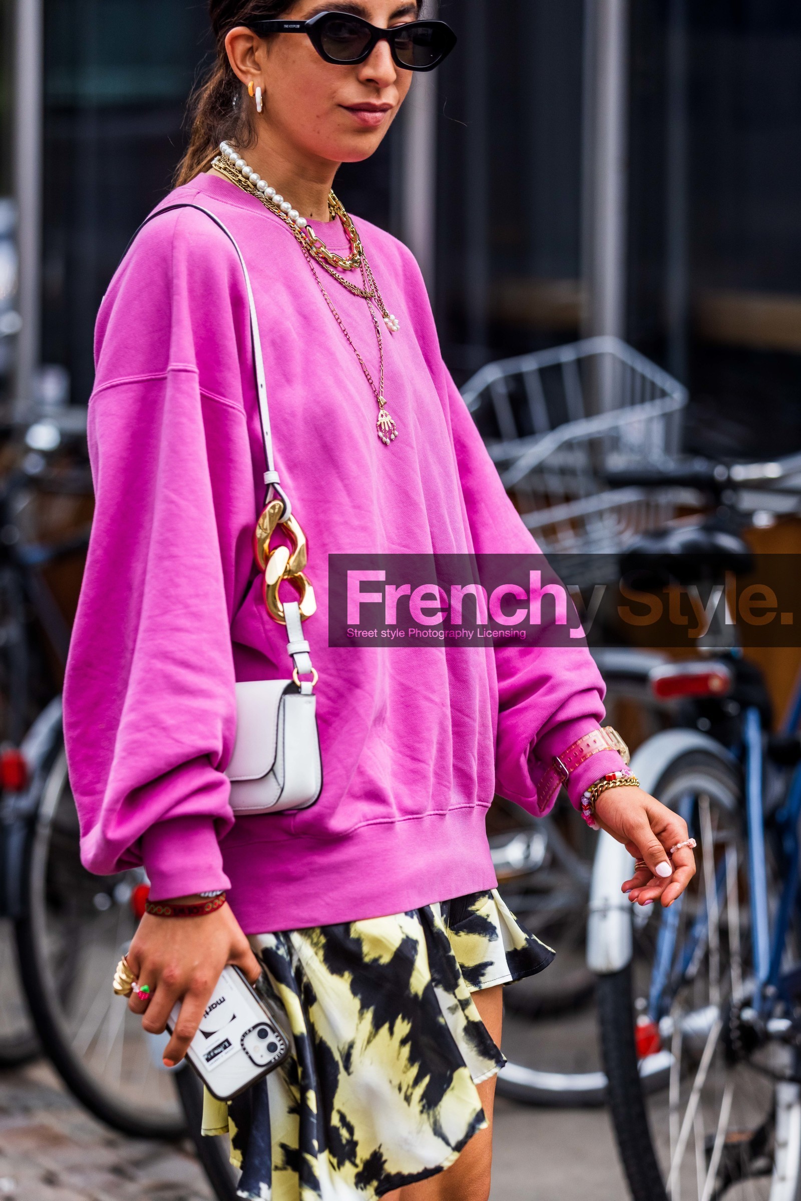Selma Kaci, pink sweatshirt, fushia sweatshirt, printed skirt, mini skirt, white leather bag, shoulder bag, j w anderson bag, chain strap bag, multi necklace, pearl necklace, golden necklace, long necklace, multi earrings, lucky charm necklace, lucky charm bracelet, baby g watch, chain necklace, the kooples sunglasses, black sunglasses, tie and dye skirt, fashion week, frenchystyle, FW, jonathan paciullo, street style, SPRING SUMMER 2022, SS 22, COPENHAGEN, CPHFW, vertical, atmosphere details