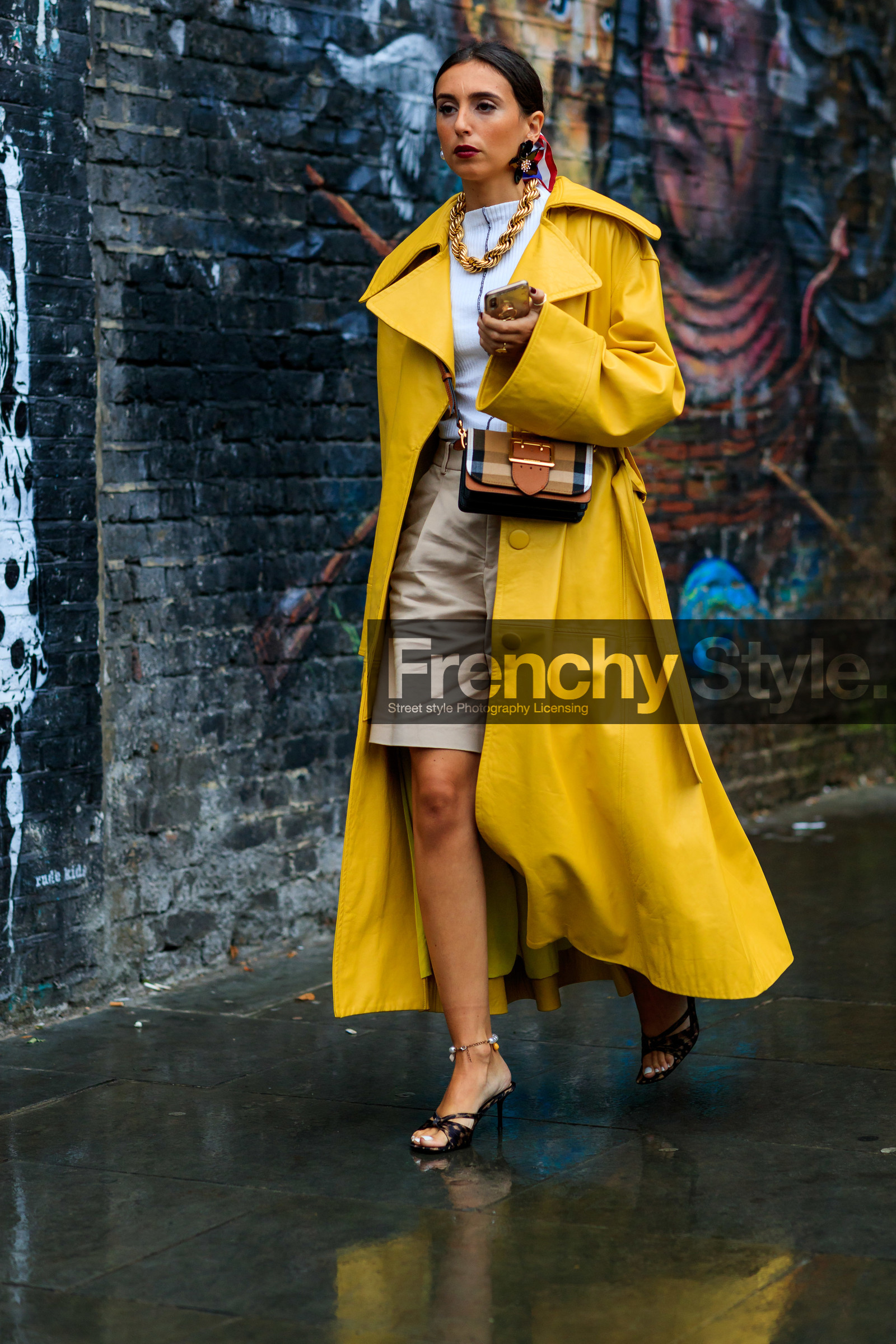 yellow trench coat, oversize trench coat, white top, big chain necklace, golden necklace, plastic earrings, flowers earrings, burberry bag, crossbody bag, checked bag, brown leather bag, big buckle bag, beige bermuda shorts, high heels sandals, high heels slippers, animal print sandals, beige leather bag, silk scarf, printed scarf, fashion week, frenchystyle, FW, jonathan paciullo, street style, vertical, full length