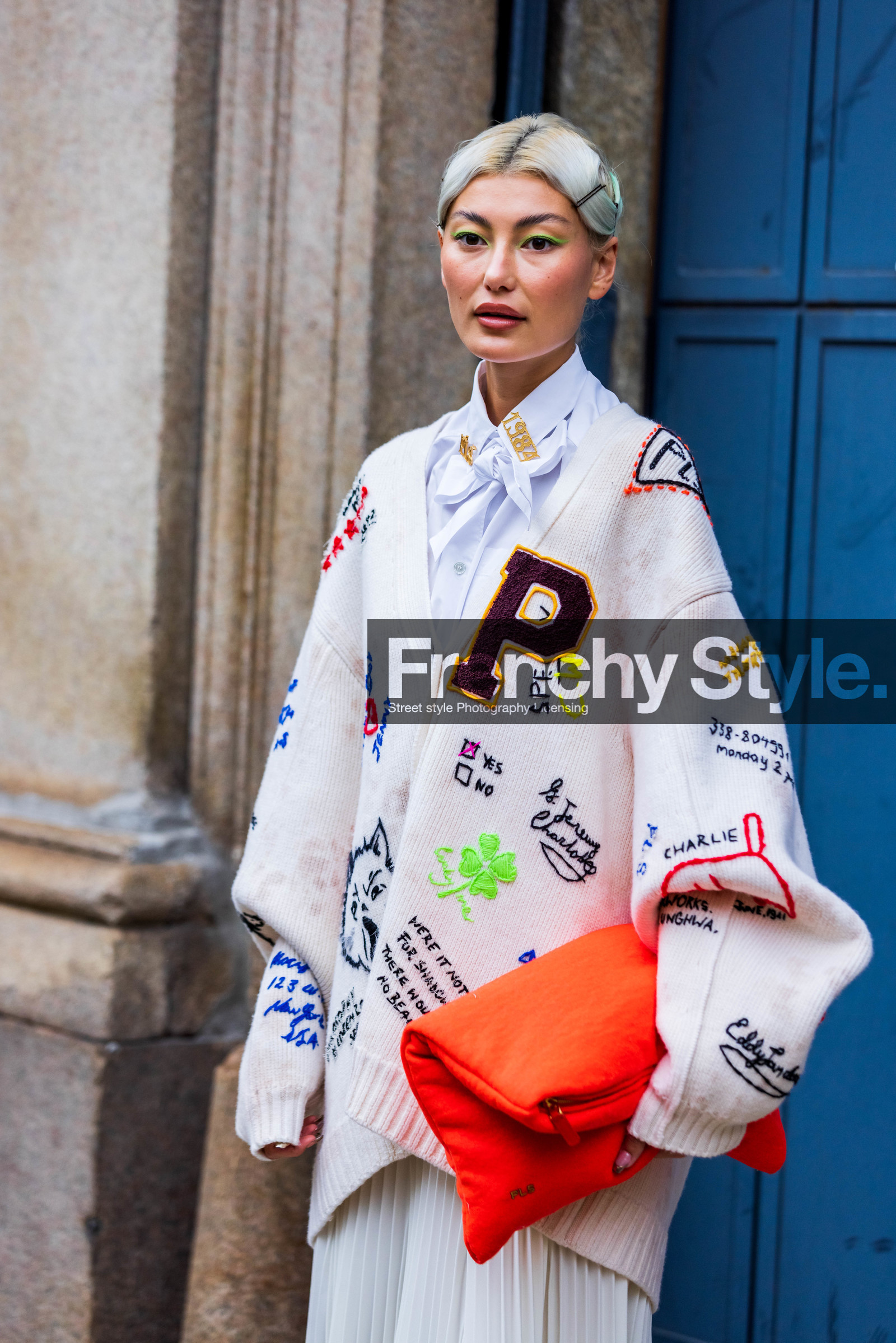Amalie Gassmann, badge, bow shirt, cardigan, color, colored bag, fluo green eyeliner, green eyeliner, makeup, orange bag, orange pouch, pleated skirt, print, printed cardigan, printed knit, shirt, skirt, white cardigan, white shirt, white skirt, fashion week, frenchystyle, FW, jonathan paciullo, street style, SPRING SUMMER 2022, SS 22, MFW, MILAN, vertical, atmosphere details